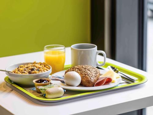 a breakfast tray with a plate of food and a glass of orange juice at ibis budget Metz Technopole in Metz