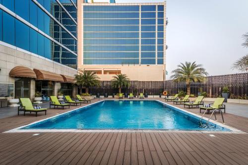 Golden Suites Gurgaon Inde Hotels في جورجاون: مسبح وكراسي ومبنى