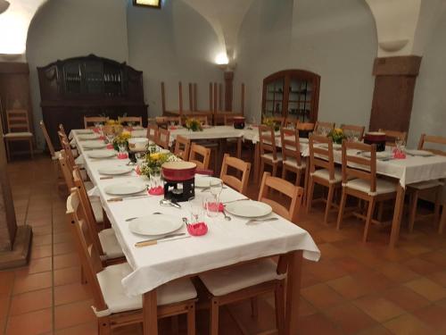 a large dining room with tables and chairs with white tablecloths at Ancien Presbytère Albert Schweitzer in Gunsbach