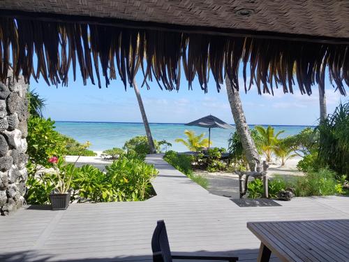 einen Holzweg, der zu einem Strand mit dem Meer führt in der Unterkunft Aitutaki Escape in Arutanga