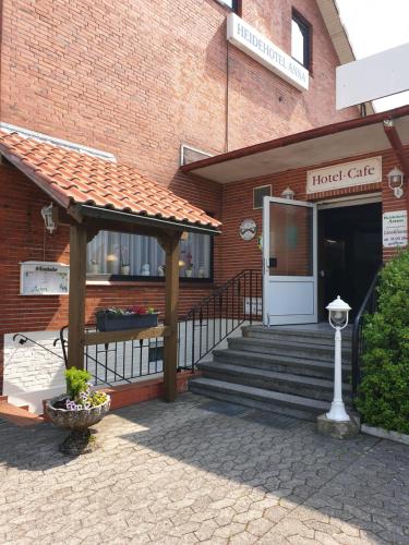 - un bâtiment avec une terrasse couverte et une entrée dans l'établissement Heidehotel Anna, à Soltau