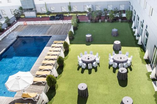 an overhead view of a patio with tables and chairs and a pool at Vértice Sevilla Aljarafe in Bormujos