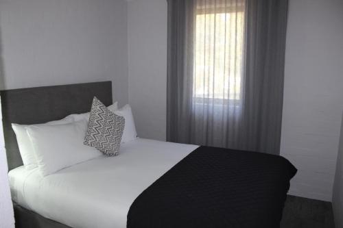 a bedroom with a white bed and a window at Atrium Hotel Mandurah in Mandurah