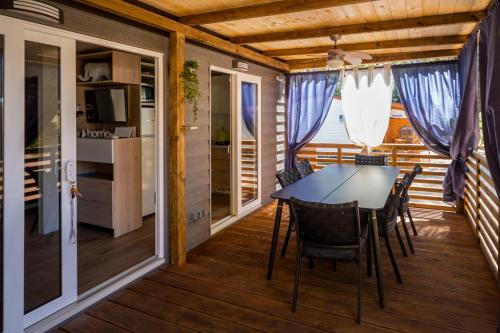 een eetkamer met een tafel en stoelen op een terras bij Mobile Home HappyNest in Biograd na Moru