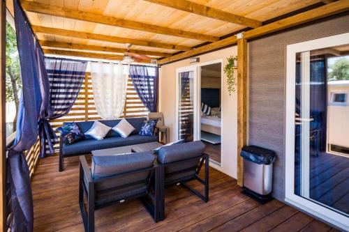 een veranda met een bank en stoelen op een terras bij Mobile Home HappyNest in Biograd na Moru