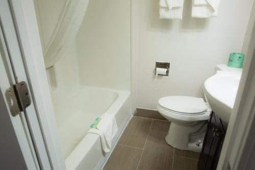 a white bathroom with a toilet and a sink at Eastern Inn in Bourne