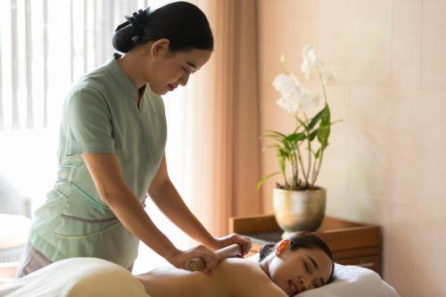 a woman is giving a woman a massage at The Sukhothai Bangkok in Bangkok