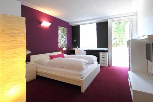 a bedroom with a white bed and a purple wall at College Garden Hotel in Bad Vöslau