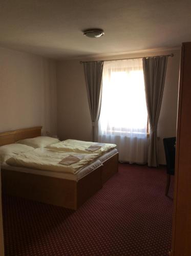 a bedroom with a bed and a large window at Hotel U Zlateho Andela in Pardubice