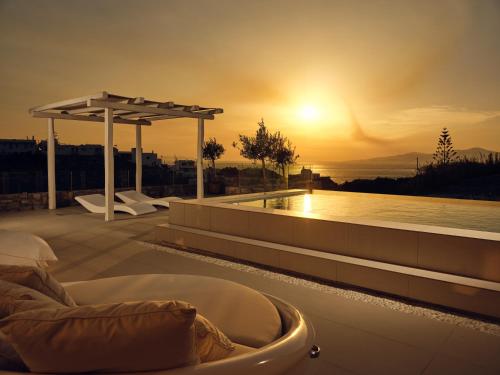 a hot tub on a roof with a sunset in the background at Arcs Suites & Residences in Mýkonos City