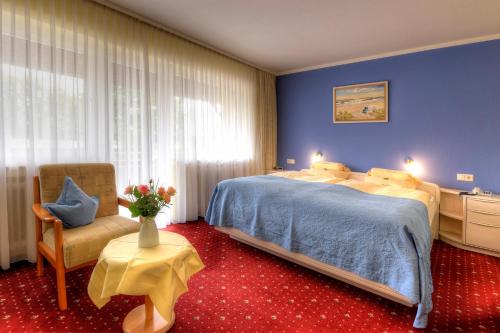 a bedroom with a large bed and a chair at Hotel Katharina Garni in Tübingen