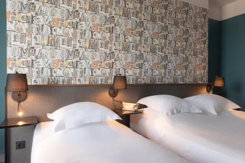 two beds in a hotel room with a wallpaper at Hôtel Bristol Reims in Reims