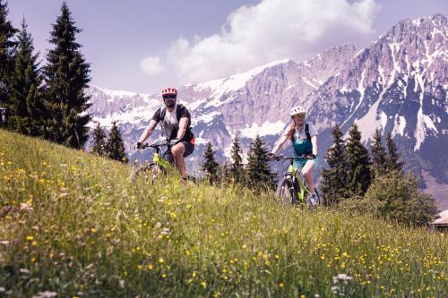 zwei Personen auf einem Hügel mit Bergen im Hintergrund Fahrrad fahren in der Unterkunft Tirol Lodge in Ellmau