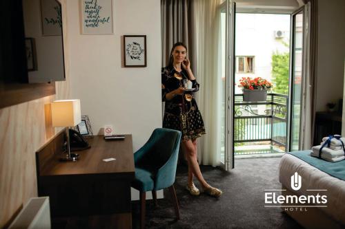 a woman standing in a hotel room talking on a phone at Hotel Elements in Novi Pazar