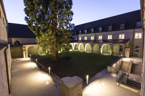 un patio con un árbol y un edificio con luces en Odalys City Dijon Les Cordeliers, en Dijon