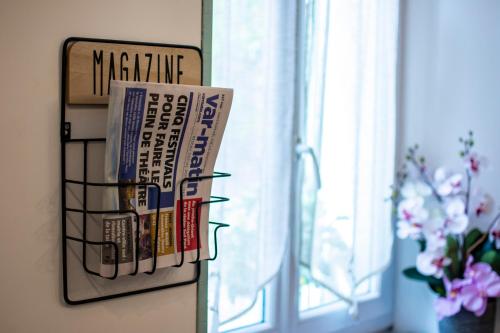 a magazine holder on a wall next to a window at Hotel Le Flore in Fréjus