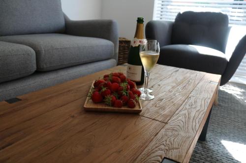 a table with a plate of strawberries and a glass of wine at City Apartment in Winchester