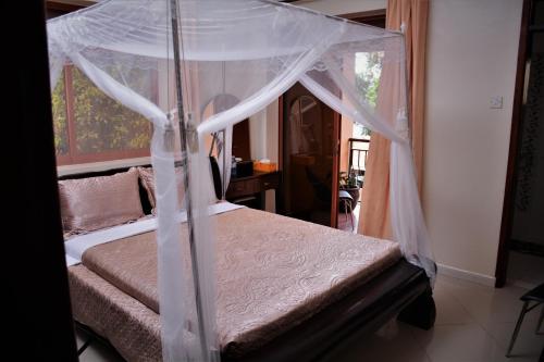 um quarto com uma cama de dossel em The Palms Beach Hotel em Entebbe