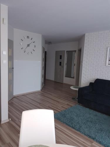 - un salon avec un canapé et un réveil sur le mur dans l'établissement Angel Apartament, à Władysławowo