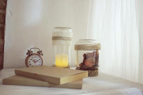 a clock and a glass jar with a candle and a book at Casa Rural Teresa in El Molar