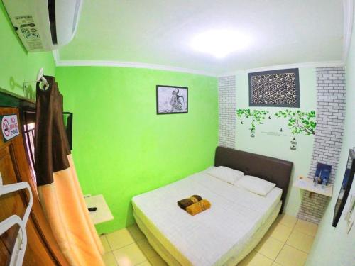 een kleine slaapkamer met groene muren en een bed bij nDalem Eyang Dwijo in Yogyakarta