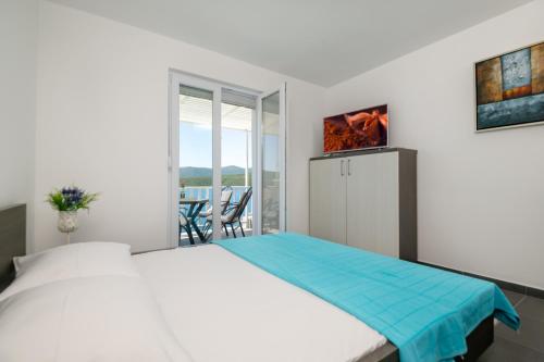 een witte slaapkamer met een bed en een balkon bij Apartments Lukrecia in Neum