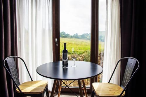 a table with a bottle of wine and two chairs at Apartamentos Estela de Altamira in Santillana del Mar