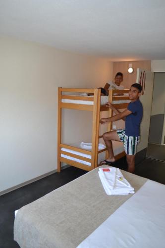 two men standing in a room with bunk beds at Hotel Formule Club in Cenon