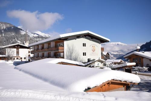 un toit enneigé d'un hôtel avec un bâtiment dans l'établissement Gästehaus Waltl, à Krimml