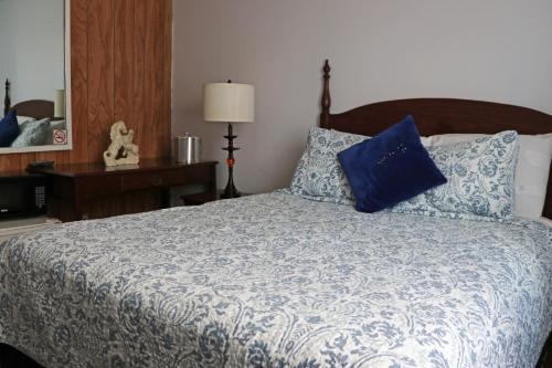 1 dormitorio con cama con almohadas azules y espejo en The Falls Family Lodge, en Niagara Falls