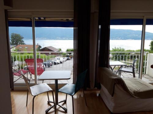 een kamer met een balkon met uitzicht op het water bij La villa Du Port in Veyrier-du-Lac