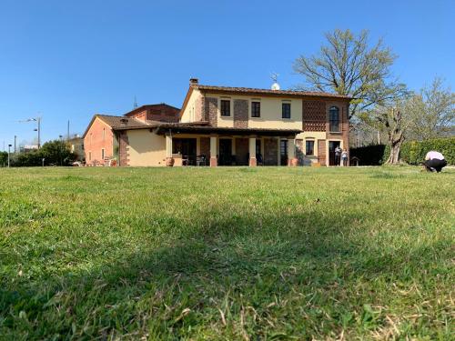 una vecchia casa su un prato con una casa di B&B La Fornace del Sole a Capannori