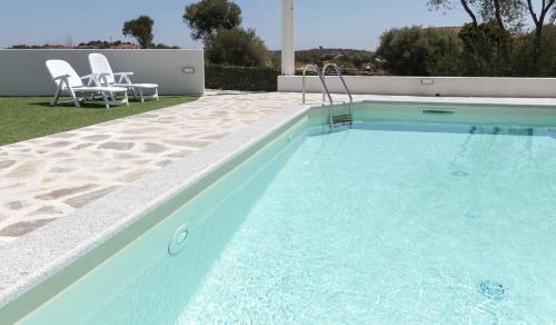 una piscina con 2 sillas y una mesa en Mediterraneo, en San Teodoro