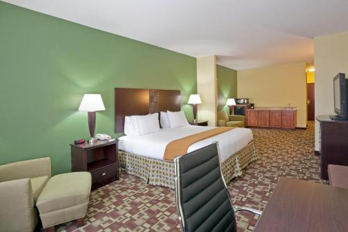 una camera d'albergo con letto, tavolo e sedie di Holiday Inn Express Hotel & Suites Dumas, an IHG Hotel a Dumas