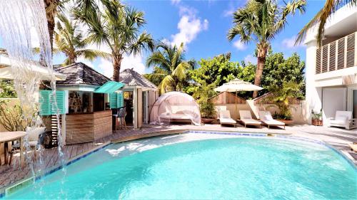 einen Pool mit Stühlen und einem Sonnenschirm neben einem Haus in der Unterkunft Hotel Les Ondines Sur La Plage in Gustavia