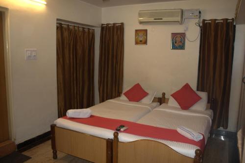 1 dormitorio con 2 camas y almohadas rojas en Nachis BNB, en Bangalore