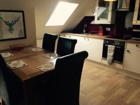 een keuken met een houten tafel met stoelen en een eetkamer bij The Royal Hotel Cromarty in Cromarty