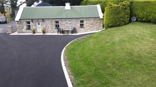 ein Steinhaus mit einem Tisch vor einer Einfahrt in der Unterkunft Swallows Cottage in Swinford