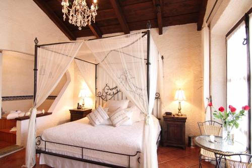 a bedroom with a canopy bed and a table at Posada El Antaño in Antigua Guatemala