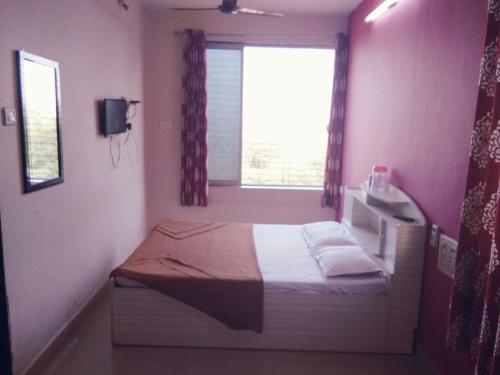 a small bedroom with a bed and a window at Relax inn in Matheran