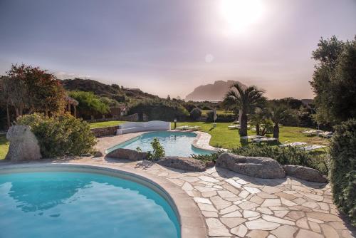 uma piscina com pedras num quintal em Hotel Ollastu em Costa Corallina