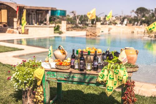 - une table avec des fruits et des bouteilles de vin à côté de la piscine dans l'établissement Agriturismo Li Calizzi Arte e Natura, à Novoli