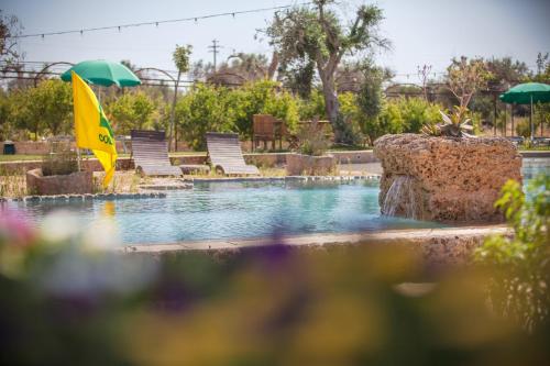 une piscine avec des chaises et un drapeau jaune dans l'eau dans l'établissement Agriturismo Li Calizzi Arte e Natura, à Novoli