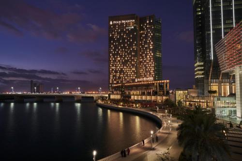 eine Stadt in der Nacht mit einem Fluss und hohen Gebäuden in der Unterkunft Four Seasons Hotel Abu Dhabi at Al Maryah Island in Abu Dhabi