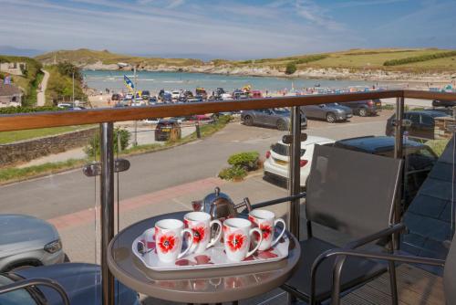 bandeja de tazas de té en una mesa en un balcón con playa en The Beach House & Porth Sands Apartments, en Newquay