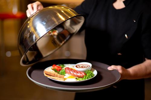 a person holding a plate of food on a tray at Hotel Complex Olimp in Umanʼ