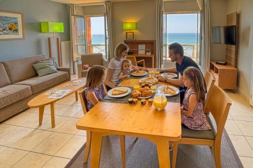 une famille assise à une table à manger pour manger dans l'établissement Residence Reine Marine, à Saint-Malo