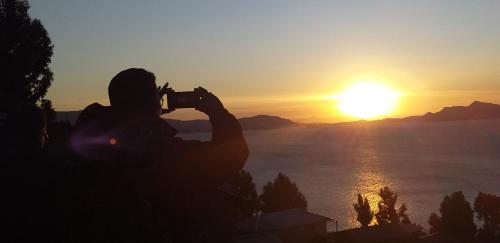 una persona tomando una foto de la puesta de sol en Titicaca Chaska Wasi Amantani, en Ocosuyo