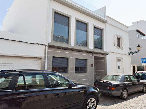 twee auto's geparkeerd voor een gebouw bij Faro Clara Suites in Faro