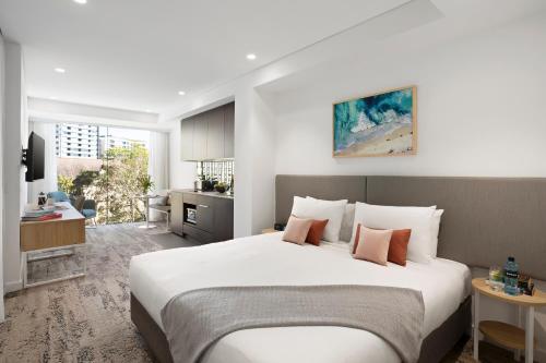 Cet appartement comprend une chambre avec un grand lit blanc et une cuisine. dans l'établissement Quest North Sydney, à Sydney